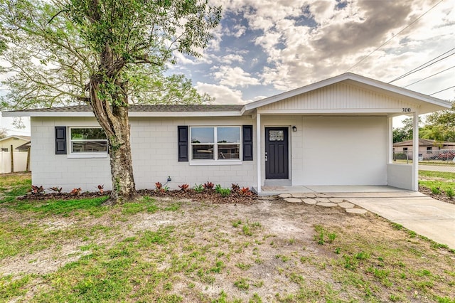 ranch-style house with concrete block siding and fence