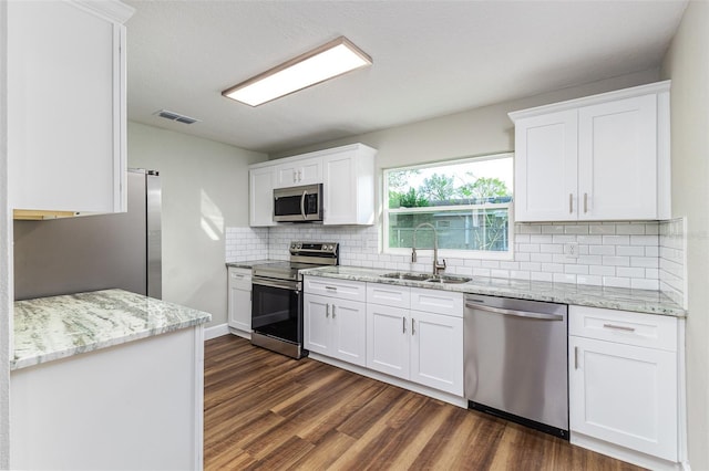 kitchen with dark wood-style floors, visible vents, a sink, appliances with stainless steel finishes, and backsplash