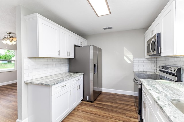 kitchen featuring stainless steel appliances, visible vents, dark wood finished floors, and white cabinets