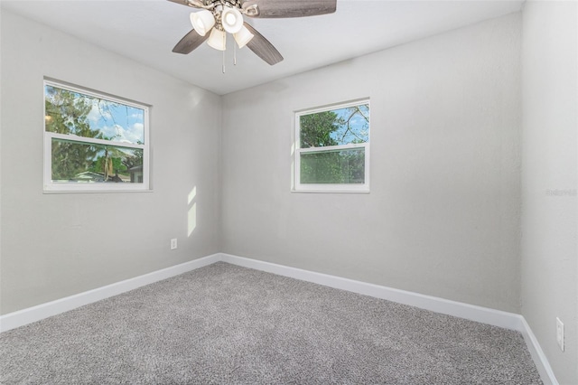 carpeted spare room featuring a ceiling fan and baseboards