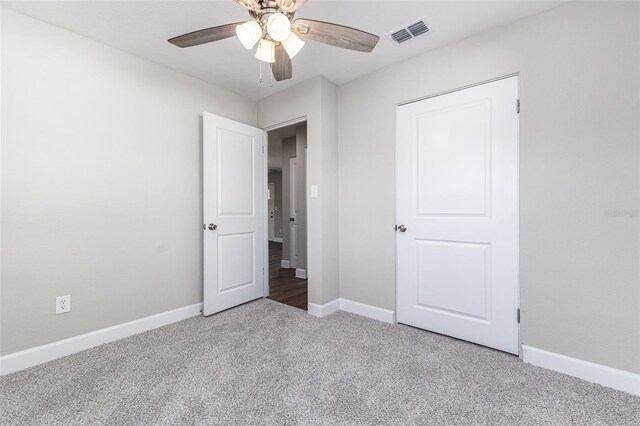 unfurnished bedroom featuring a ceiling fan, baseboards, visible vents, and carpet floors