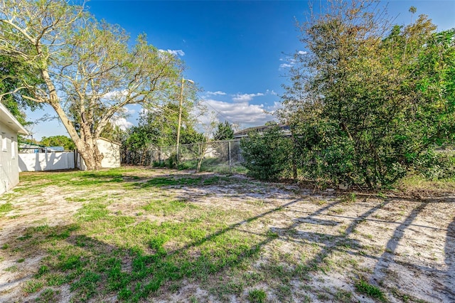 view of yard with an outdoor structure, a fenced backyard, and a shed