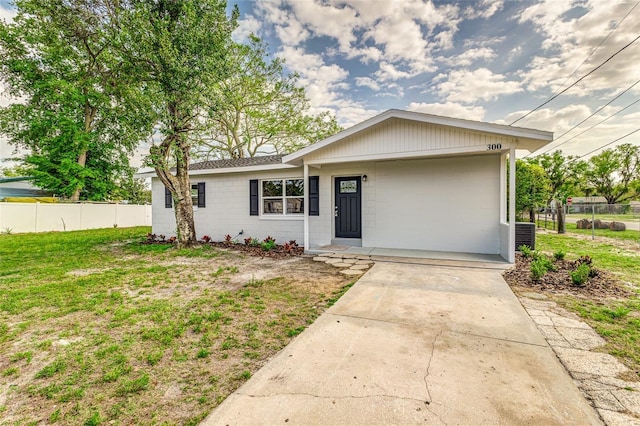 ranch-style home with driveway, concrete block siding, a front yard, and fence