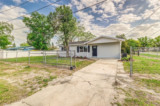 view of front of house featuring a gate, fence, concrete driveway, a front lawn, and central air condition unit