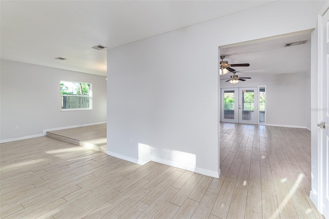 empty room with french doors, visible vents, light wood-style flooring, and baseboards