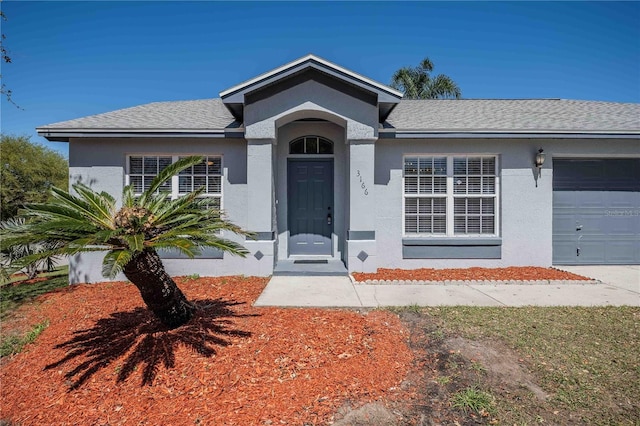 single story home featuring stucco siding, a garage, and roof with shingles