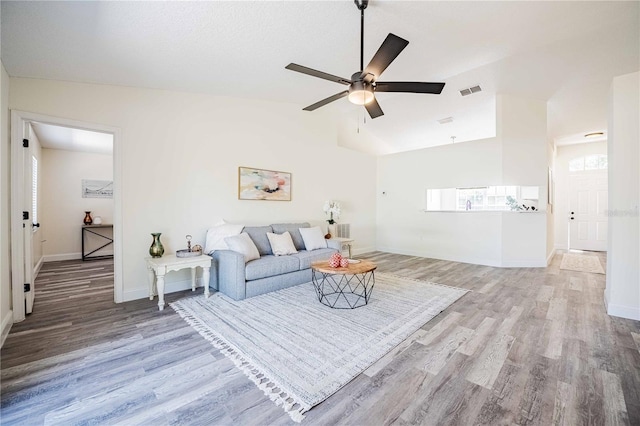 living area with baseboards, lofted ceiling, ceiling fan, and wood finished floors