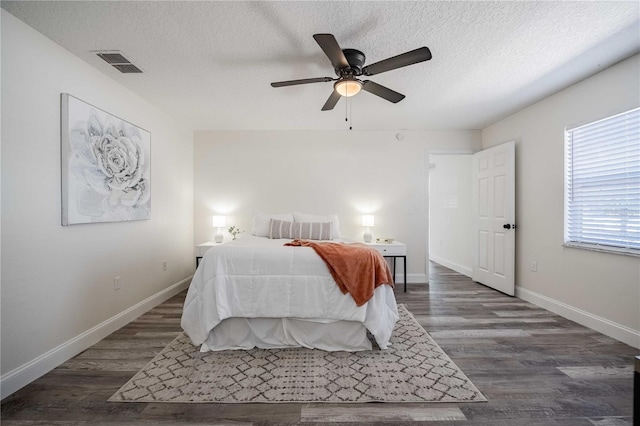 bedroom with dark wood-type flooring, baseboards, visible vents, and a textured ceiling