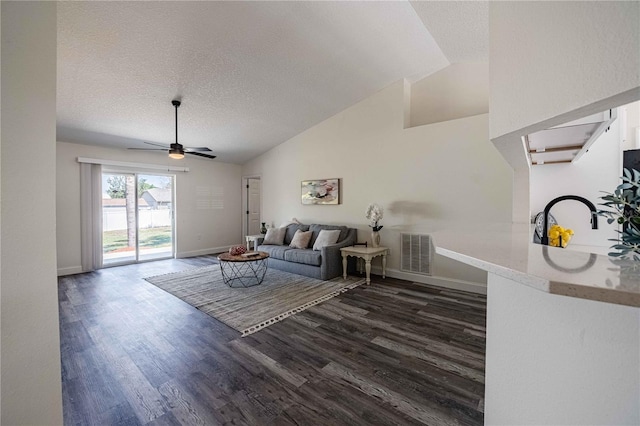 living area featuring visible vents, a ceiling fan, a textured ceiling, dark wood-style floors, and baseboards