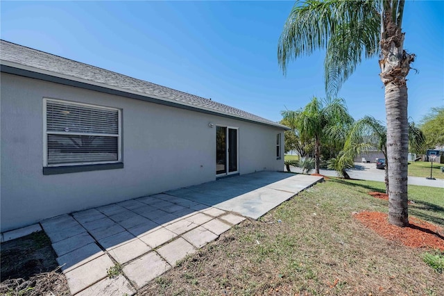 rear view of house featuring stucco siding, a patio, and a yard