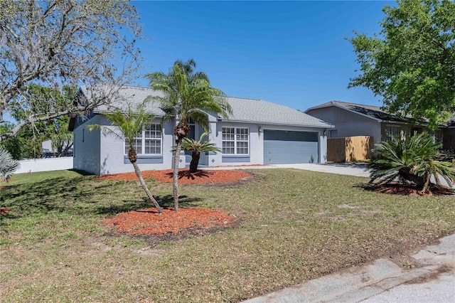 ranch-style home featuring fence, concrete driveway, a front yard, stucco siding, and a garage