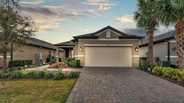 view of front of home featuring a garage, central AC unit, decorative driveway, and stucco siding