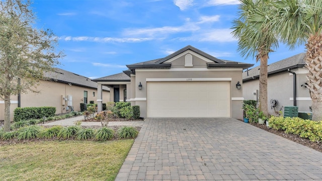 view of front of home featuring an attached garage, central air condition unit, decorative driveway, and stucco siding