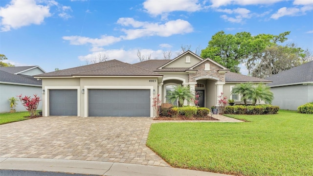 view of front facade featuring a front yard, roof with shingles, an attached garage, stucco siding, and decorative driveway