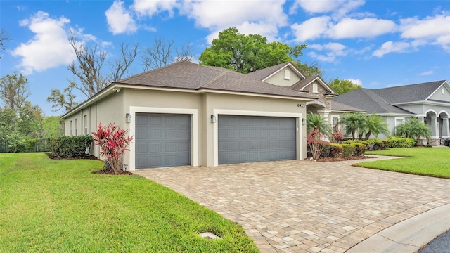 view of front of house with decorative driveway, a front yard, an attached garage, and stucco siding