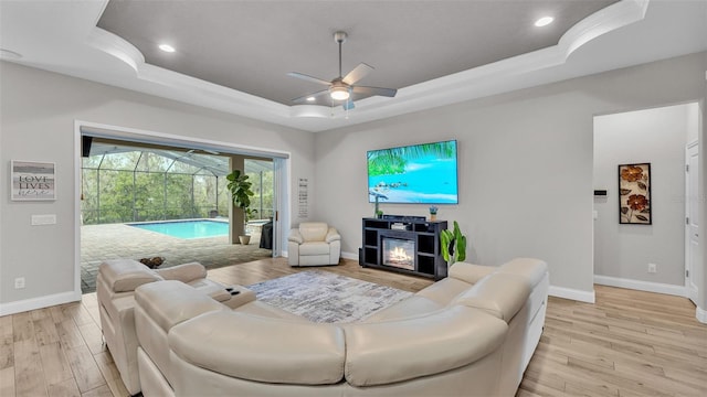 living area featuring recessed lighting, light wood-type flooring, a raised ceiling, and a sunroom