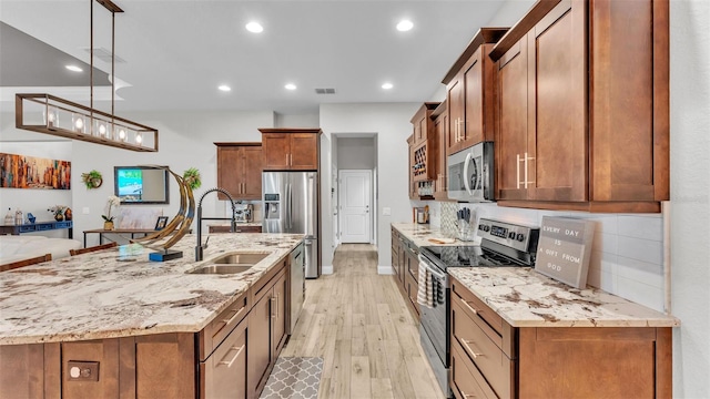 kitchen with visible vents, a sink, stainless steel appliances, brown cabinets, and backsplash