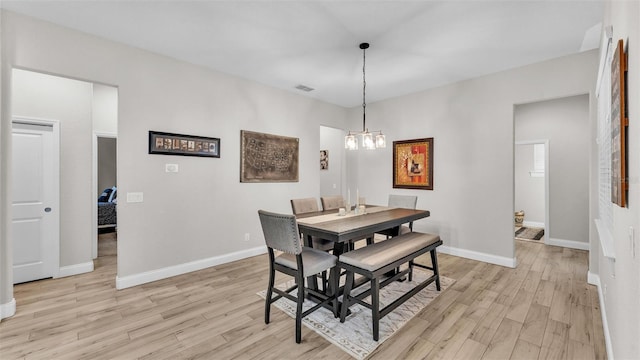 dining space featuring a notable chandelier, baseboards, and light wood finished floors