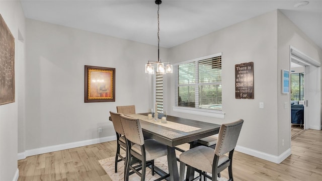 dining area featuring an inviting chandelier, baseboards, and light wood finished floors