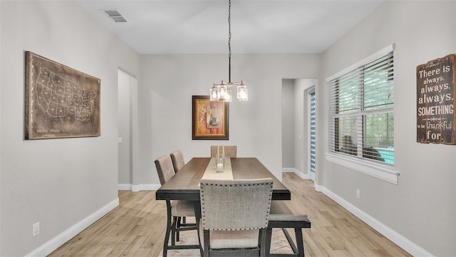 dining space featuring light wood-type flooring, visible vents, baseboards, and a chandelier