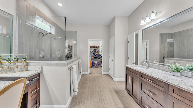 full bath with baseboards, vanity, a walk in closet, and walk in shower