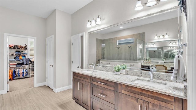 full bathroom featuring a sink, a spacious closet, double vanity, and a tile shower