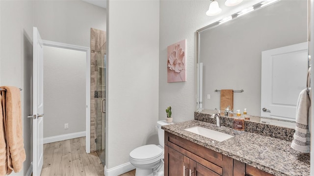 full bath with toilet, wood finished floors, a shower stall, baseboards, and vanity