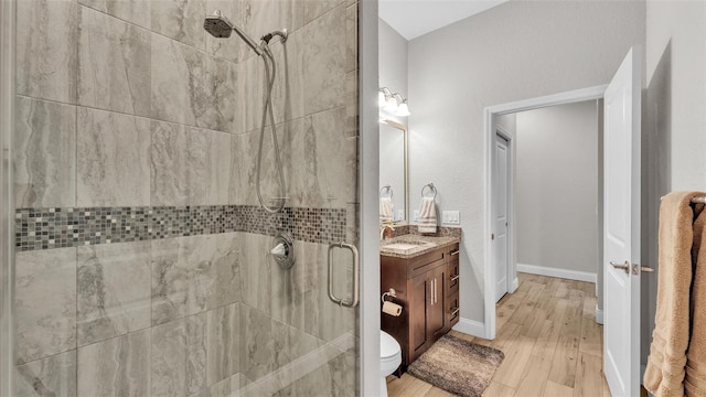 full bathroom with a shower stall, vanity, baseboards, and wood finished floors