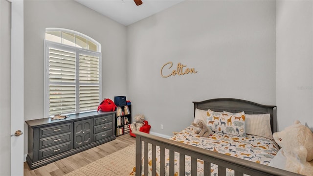 bedroom with a ceiling fan, baseboards, and light wood-type flooring