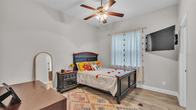 bedroom featuring light wood-style flooring, a ceiling fan, and baseboards