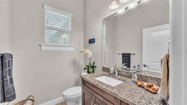 bathroom with toilet, vanity, and baseboards