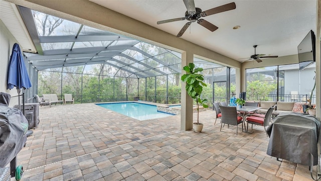 view of pool featuring a lanai, a pool with connected hot tub, ceiling fan, and a patio area