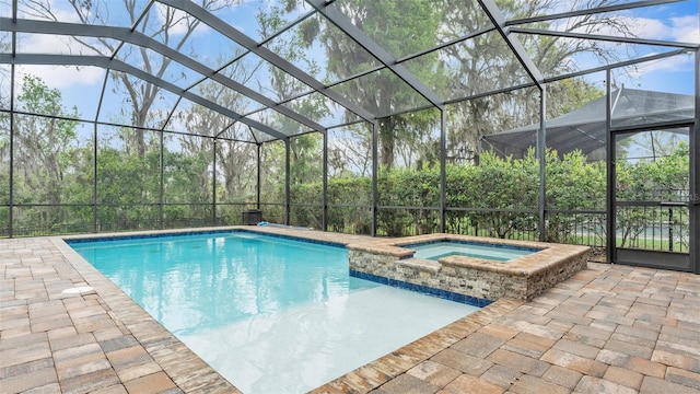 view of pool featuring glass enclosure, a patio, and a pool with connected hot tub