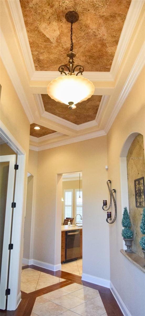 interior space featuring light tile patterned floors, baseboards, coffered ceiling, and ornamental molding