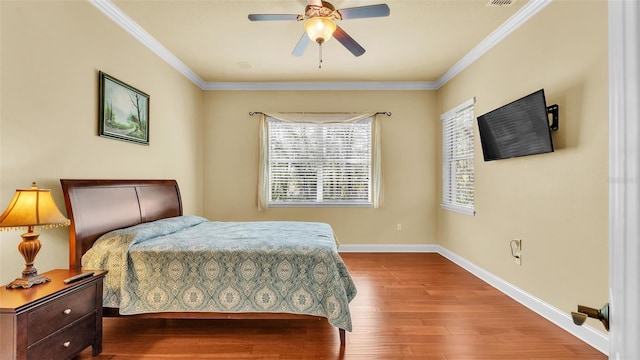 bedroom with ceiling fan, wood finished floors, visible vents, baseboards, and ornamental molding