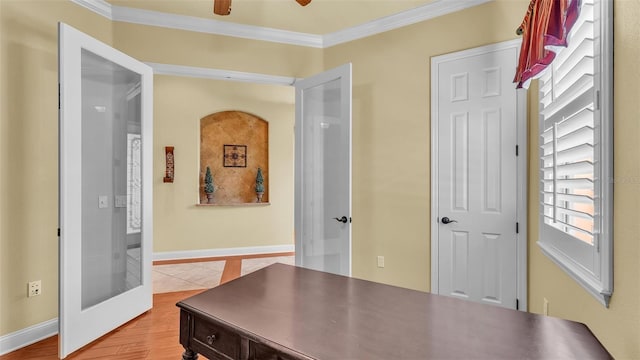 office space with baseboards, light wood-type flooring, a ceiling fan, and crown molding