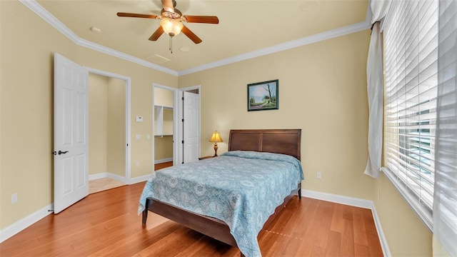 bedroom with a spacious closet, baseboards, crown molding, and wood finished floors