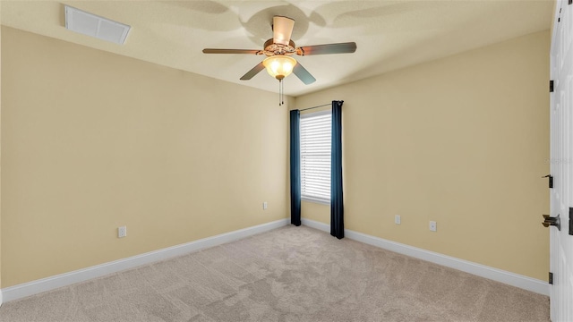 spare room featuring baseboards, a ceiling fan, visible vents, and light colored carpet