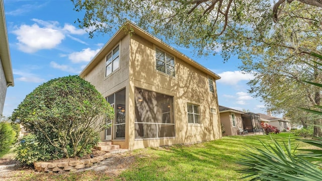 view of side of home with a sunroom, stucco siding, and a yard