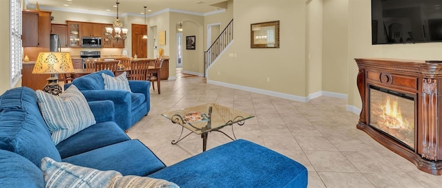 living area featuring baseboards, light tile patterned flooring, ornamental molding, and a glass covered fireplace