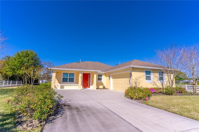 view of front of house with stucco siding, fence, concrete driveway, a front yard, and an attached garage