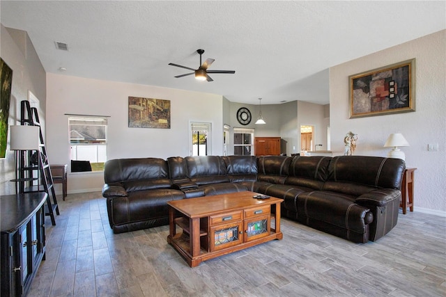 living area with visible vents, plenty of natural light, light wood-style floors, and a ceiling fan