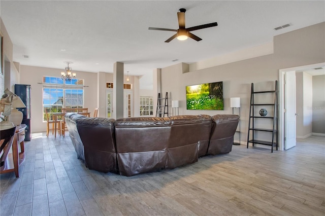 living room featuring visible vents, ceiling fan with notable chandelier, baseboards, and wood finished floors