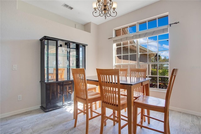 dining area featuring a notable chandelier, visible vents, baseboards, and wood finished floors