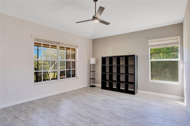 empty room with a ceiling fan, baseboards, and wood finished floors