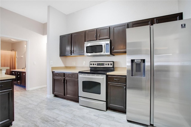 kitchen featuring dark brown cabinets, appliances with stainless steel finishes, light countertops, and baseboards