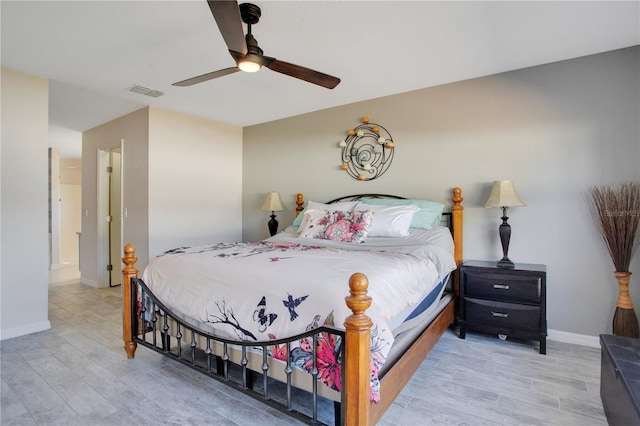 bedroom featuring a ceiling fan, wood finished floors, visible vents, and baseboards