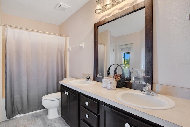 bathroom with a sink, visible vents, toilet, and double vanity