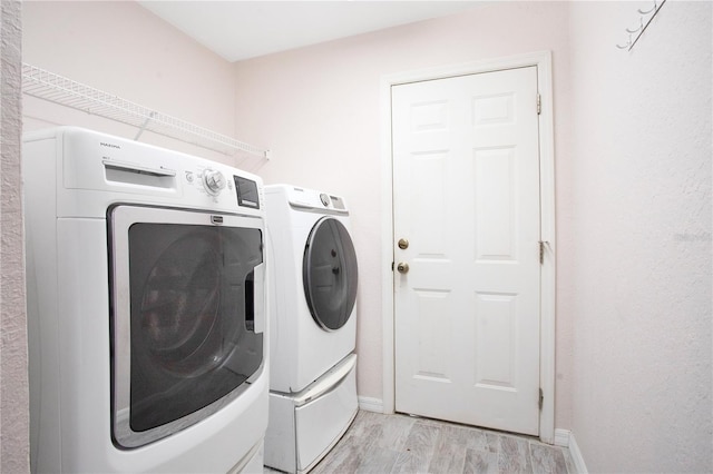 clothes washing area featuring laundry area, light wood-style flooring, baseboards, and independent washer and dryer