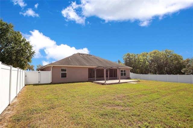 back of house with a fenced backyard, a yard, a patio, and a gate